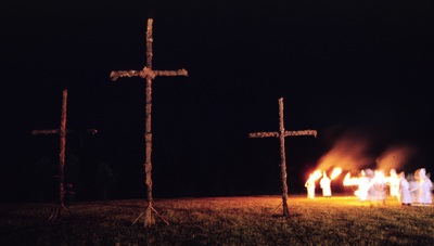 KKK members carry torches across a field in western Greene County Missouri in the early 1990's. (Copyright John S. Stewart/LEFTeyeSTORIES.com)